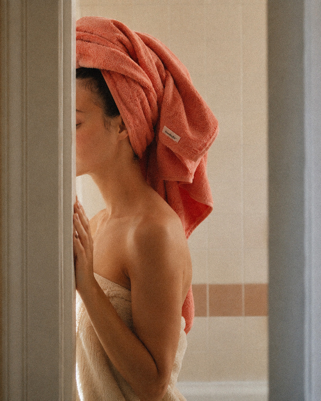 Person wearing a coral towel wrapped around their hair after a shower